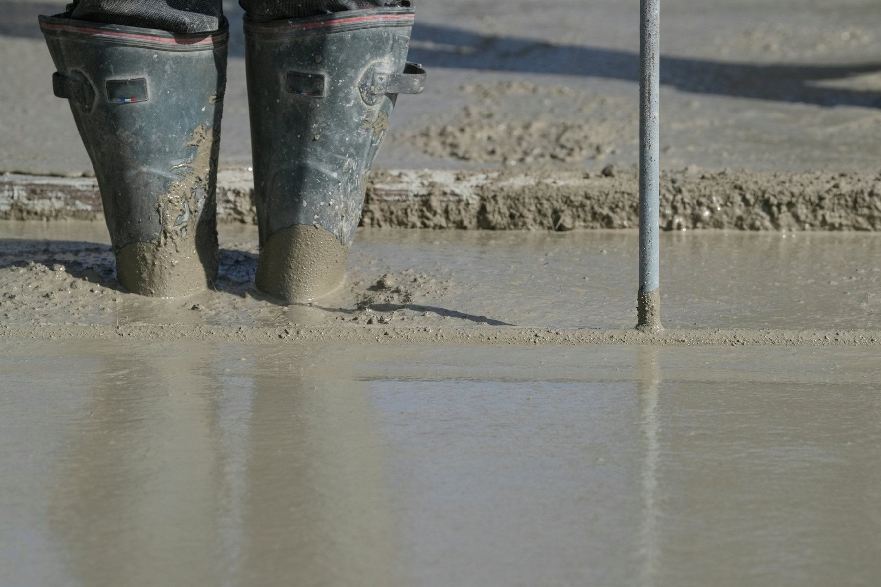 Taze dökülmüş betonun içinde duran usta botları